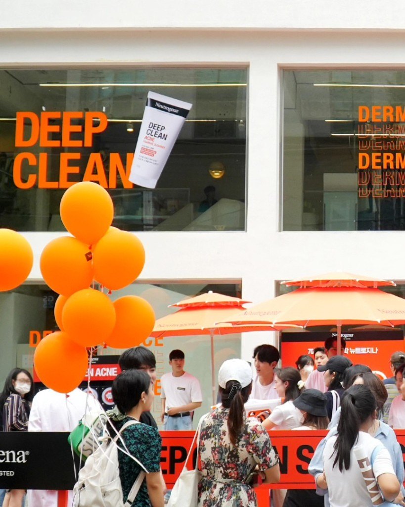 오렌지 풍선과 DEEP CLEAN 그래픽으로 꾸민 뉴트로지나 성수 팝업 외관과 방문객